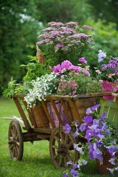 a wagon filled with lots of flowers sitting on top of a lush green field