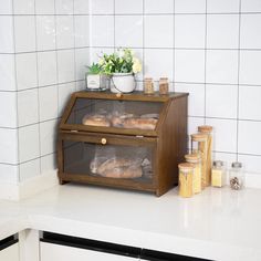 two breads are sitting on the counter in front of a white tiled wall and some jars