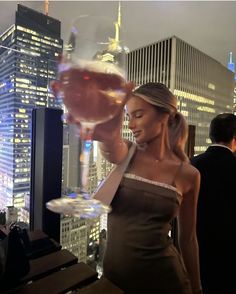 a woman holding a wine glass in front of a cityscape