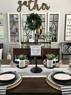 a dining room table set for two with place settings and plates on the centerpiece