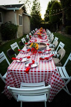 a long table covered in red and white checkered cloths with sunflowers