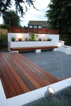 a wooden bench sitting on top of a cement floor next to a tree and fence