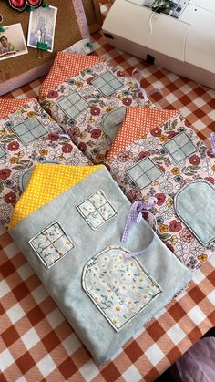 four quilts laid out on top of a table next to a sewing machine and other crafting supplies