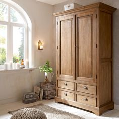 a large wooden armoire sitting next to a window in a room with white walls