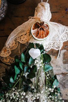 an arrangement of flowers and fruit is displayed on a table with doily hanging from it