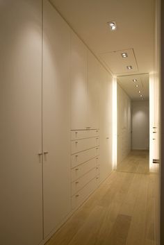 an empty hallway with white walls and drawers