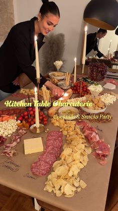 a woman sitting at a table filled with food and candles in front of her, surrounded by other foods