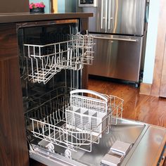 an open dishwasher in a kitchen with stainless steel appliances and wood flooring