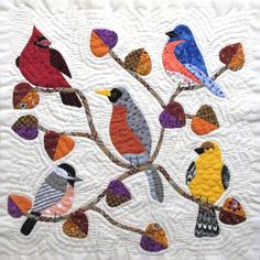 a quilted wall hanging with colorful birds on it's tree branch and leaves