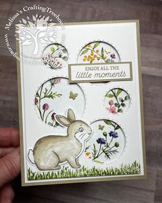 a hand holding up a card with an image of a bunny and flowers on it