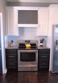 a kitchen with white cabinets and stainless steel appliances, including a silver stove top oven