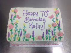 a birthday cake with white frosting and pink flowers on the side that says happy 70th birthday kathy