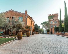 an old brick building with lots of trees in the front yard and walkway leading up to it