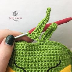 someone is crocheting an apple with a green and yellow face on the side