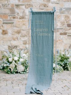 a blue banner with the words lauren and james on it sitting in front of some flowers