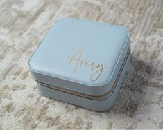 a small blue box with the word avery written on it sitting on a white carpet