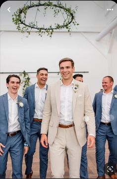 a group of men standing next to each other wearing suits and smiling at the camera