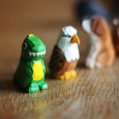 three small plastic animals sitting on top of a wooden table