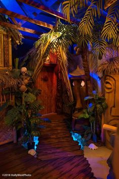 the entrance to a tropical themed room with palm trees and other plants on either side