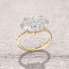 an oval shaped diamond ring on a wooden surface with the center stone in yellow gold