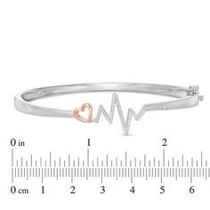 Pack a big visual punch with this diamond bangle bracelet. Crafted in sterling silver and 10K rose gold, this charming design shows a sparkling diamond-lined silver heart rhythm next to a rose gold heart outline. Radiant with 1/5 ct. t.w. of diamonds and a brilliant buffed luster, this hinged bangle measures 7.0 inches in circumference and secures with a tongue and groove clasp. Heart Rhythm, Diamond Bangle Bracelet, Heart Outline, Diamond Bangles Bracelet, Peoples Jewellers, Rose Gold Heart, Sparkling Diamond, Tongue And Groove, Diamond Bangle