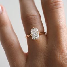 a woman's hand with a diamond ring on top of her finger, showing the center stone