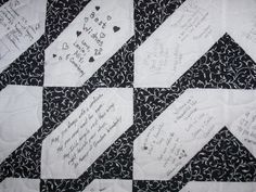 a quilt with writing on it sitting on top of a black and white checkered table cloth