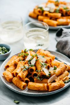 pasta with sauce and parmesan cheese on a plate next to glasses of water