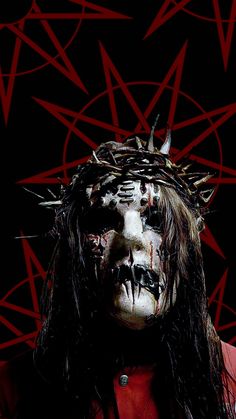 a man with long hair and makeup is wearing a crown of thorns on his head