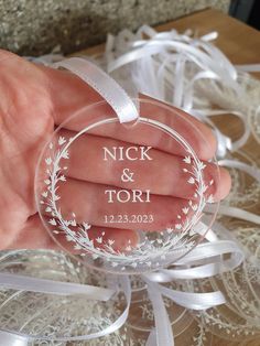 a hand holding a glass ornament with the words nick and tori on it