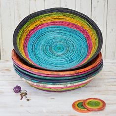 several colorful bowls stacked next to each other on a wooden table with two small buttons