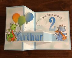 an open birthday card with balloons and animals on the front, in blue and white