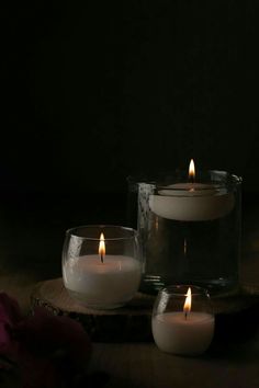 three lit candles sitting on top of a wooden table