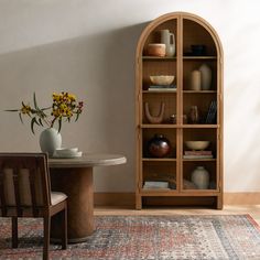 a room with a table, chairs and vases on the shelf next to it