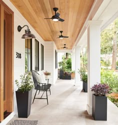 a porch with two chairs and three planters on the side walk next to it