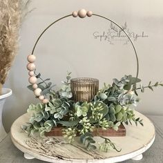 a white table topped with a vase filled with flowers and greenery next to a candle