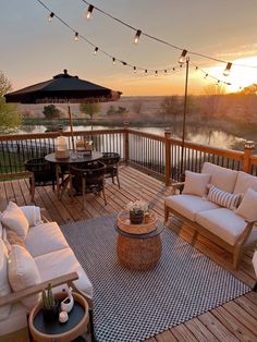 an outdoor deck with patio furniture and string lights strung over the top of it at sunset