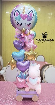 a pink table topped with balloons and a stuffed animal