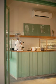 a coffee shop with green walls and white counter tops, along with a menu on the wall