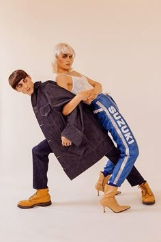 two people are posing for a photo in front of a white background, one is holding the other's leg