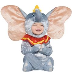 a baby in an elephant costume sitting on the ground with its trunk up and eyes closed