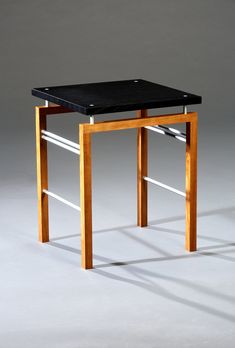 a wooden table with a black top and metal bars on the legs, against a gray background