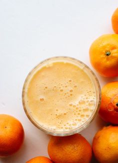 an orange juice in a glass surrounded by oranges