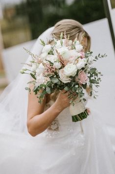 a woman in a wedding dress holding a bridal bouquet with white and pink flowers