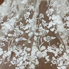 white flowers and leaves are on the sheer organ - lace fabric that has been embroidered onto it