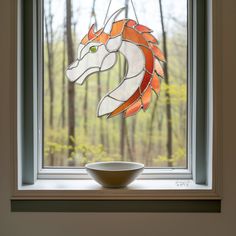 a bowl sitting on top of a window sill next to a stained glass horse head