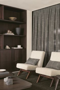 two white chairs sitting in front of a book shelf