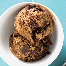 three scoops of ice cream in a white bowl on a blue surface with spoons