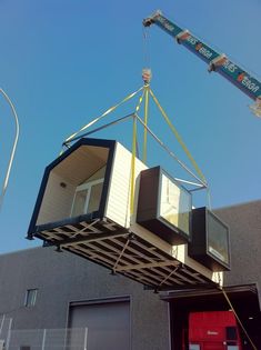 a crane is lifting a house out of the garage