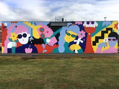 a large colorful mural on the side of a building in front of a grassy field